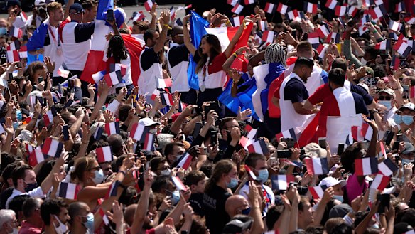 Fans wave French flags and cheer in the Olympics fan zone at Trocadero Gardens in front of the Eiffel Tower.