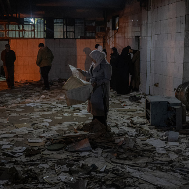 A woman looks over one of many documents and papers strewn about a section of Sednaya, a notorious prison on the outskirts Damascus.