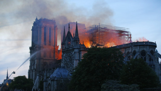 A firefighter tackles the blaze as flames and smoke rise from Notre-Dame cathedral as it burns in Paris.