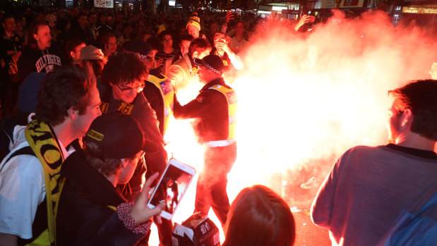 Police move in after a man sets off a flare during celebrations in Swan Street after Richmond's grand final win.