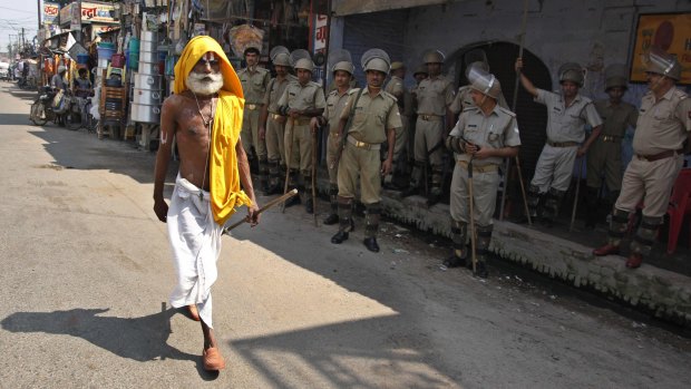A Hindu holyman walks past Indian security men standing guard in Ayodhya, India, during clashes in 2010. 
