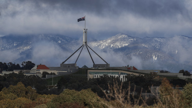 Parliament House with snow-dusted mountains surrounding the ACT after a blizzard delivered snow overnight in Canberra and parts of NSW.