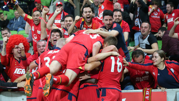 Reds ahead: Nikola Mileusnic celebrates with teammates and away fans after opening the scoring for Adelaide.