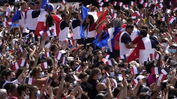 Fans wave French flags and cheer in the Olympics fan zone at Trocadero Gardens in front of the Eiffel Tower.