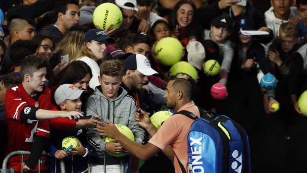 Nick Kyrgios signs autographs for fans after winning his first-round match against Lorenzo Sonego.