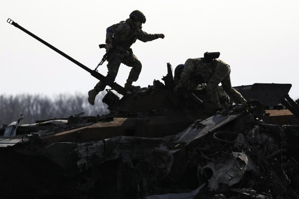 A Ukraine serviceman stands on a Russian tank in Bucha, the scene of a civilian massacre.