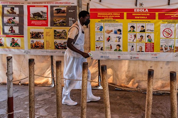 A health worker walks past Ebola warning and instruction posters at a temporary health clinic at the Mpondwe border crossing linking Uganda and the DRC on June 4.