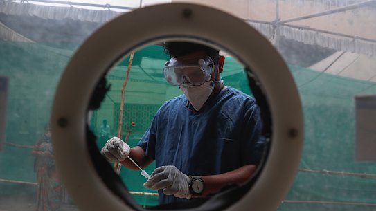 A health worker collects nasal swab samples at a COVID-19 testing center in Hyderabad, India. 