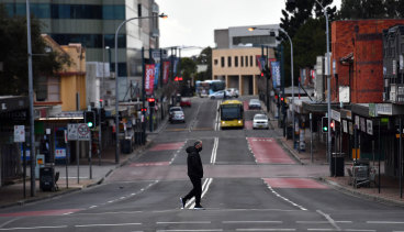 A lone person walks across Moore Street, Liverpool as Sydney bunkers down under tightened restrictions. 