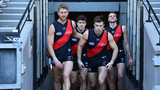 Dyson Heppell and Zach Merrett of the Bombers lead their teammates out.