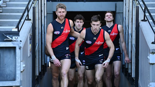 Dyson Heppell and Zach Merrett of the Bombers lead their teammates out.