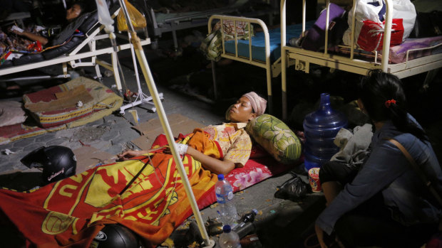 A woman lays while being treated outside at Army hospital following earthquakes and a tsunami in Palu, Central Sulawesi.