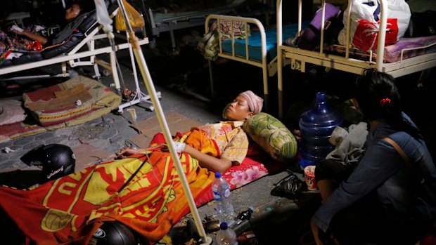 A woman lays while being treated outside at Army hospital following earthquakes and a tsunami in Palu, Central Sulawesi.