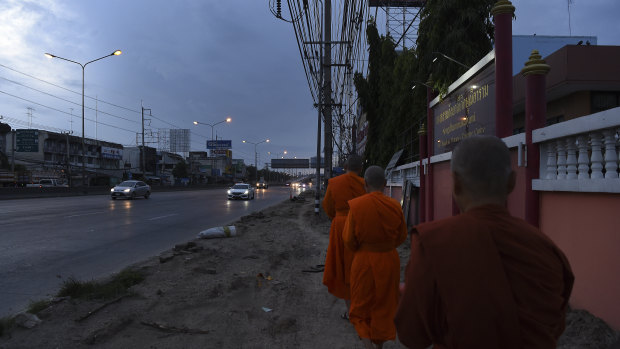 Female Theravada Buddhist monks walk the streets on their alms round - food offerings from locals that they will take back to the Songdhammakalyani Monastery to share.