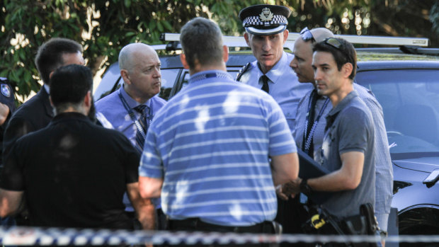Police Inspector Daniel Bragg (second from right) speaks with fellow officers at the scene.