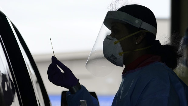 University of Washington research coordinator Rhoshni Prabhu holds up a swab after testing a passenger at a free COVID testing site in Seattle.