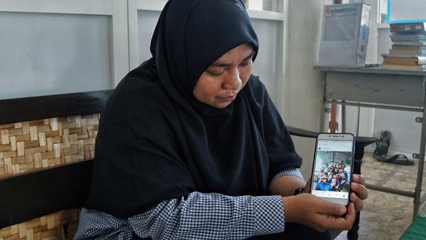 Hafidatur Romlah, who taught some of Dita Oeprianto's children, shows a picture of one of them on a school field trip.