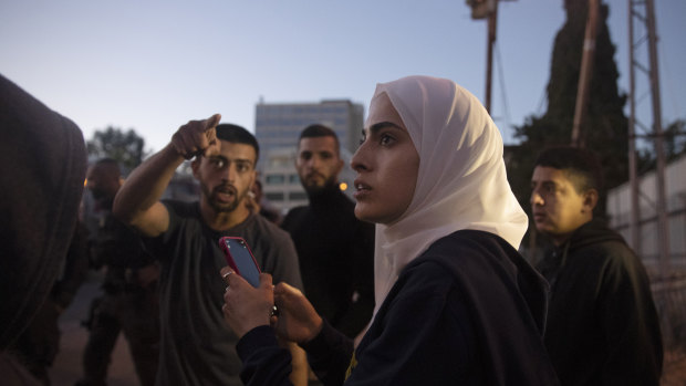 Palestinian activist Muna al-Kurd, centre, stands with other activists as Israeli police approach their friends repairing a mural that was defaced by a Jewish settler, in the Sheikh Jarrah neighborhood of east Jerusalem.