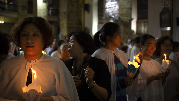 Members of the faithful hold candles during a mass at the Cathedral of the Immaculate Conception, a government-sanctioned Catholic church in Beijing. 