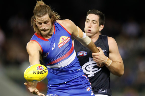 Josh Bruce attempts a kick under pressure from Carlton star Jacob Weitering.