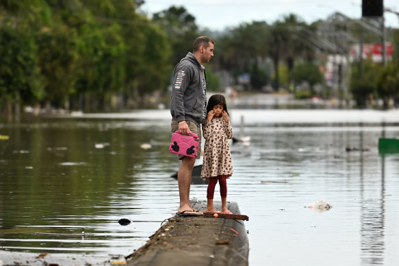 Father and daughter survey the flood damage in Lismore earlier this year. Increased floods have been linked to climate change.