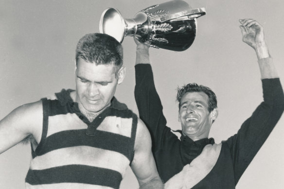 Richmond captain Fred Swift holds aloft the premiership cup, beside Geelong captain Polly Farmer. 