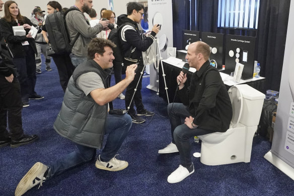 A booth worker, right, being  interviewed about U-SCAN,  a ‘health lab’ which sits within any toilet bowl.