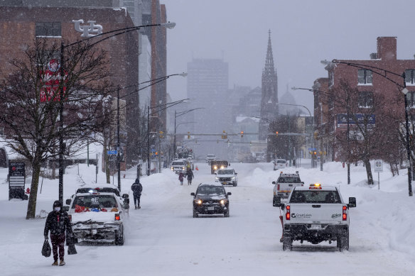 People and vehicles move about Main Street in Buffalo after a massive snow storm blanketed the city.