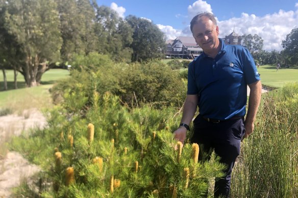 Royal Sydney Golf Club landscape architect Harley Kruse next to a patch where the grass was ripped out, watering was stopped and native plants were replanted and self-seeded in the sand.