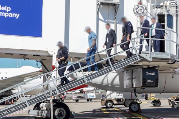 Ben Roberts-Smith is escorted off his flight upon arrival at Sydney Airport on Tuesday by AFP officers.