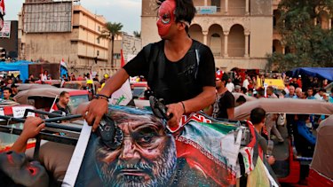 A protester hits a poster showing the leader of the Iranian Revolutionary Guard's foreign wing, or Quds Force, General Qassim Soleimani with a shoe.