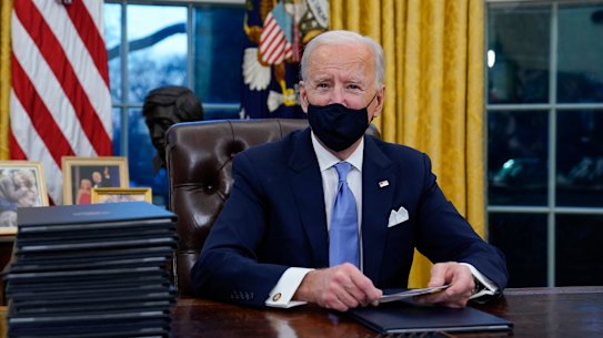 US President Joe Biden prepares to sign his first executive orders in the Oval Office of the White House.