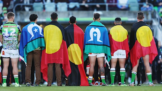 Canberra Raiders players with Aboriginal and Torres Strait Islander flags before their Indigenous Round game last week.