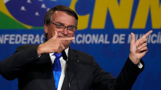 Brazilian President Jair Bolsonaro makes his signature gun-finger gesture at the opening of the national mayors’ meeting in Brasilia in April.
