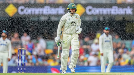 Australia’s Usman Khawaja runs back to the pavilion as it starts to rain at the Gabba.
