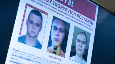 Russian Yevgeniy Polyanin, wanted by the FBI, is displayed on monitors as Attorney General Merrick Garland accompanied by Deputy Attorney General Lisa Monaco and FBI Director Christopher Wray speak in Washington. 