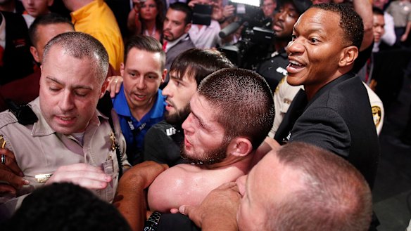 Khabib (bottom centre) is surrounded by police and security after the fight.