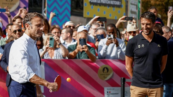 French President Emmanuel Macron plays table tennis while Paris 2024 Olympics Organising Committee President Tony Estanguet looks on at a pre-Games event in Paris.