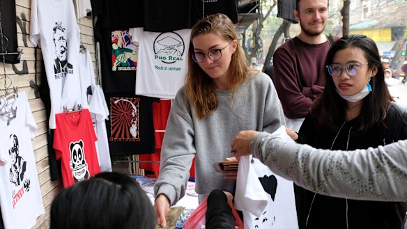 Denisa Sumska from the Czech Republic buys Trump and Kim T-shirts at Thanh’s shop.