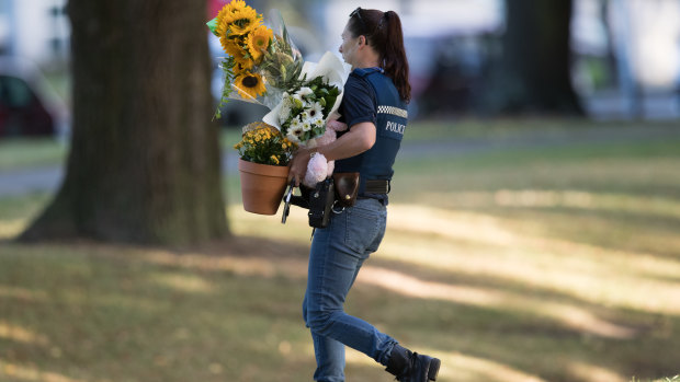 New Zealand police carry flowers left by well wishers to the Al Noor Mosque. 