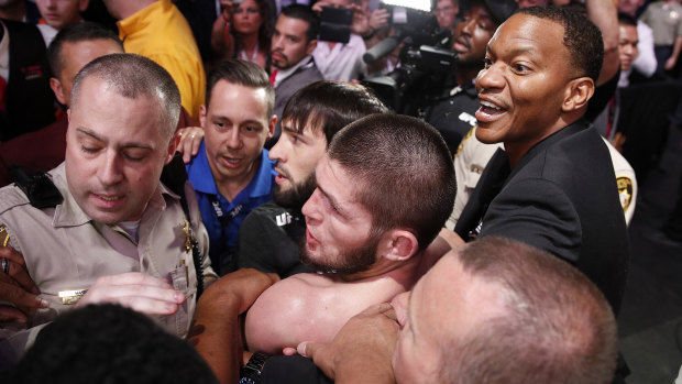 Khabib (bottom centre) is surrounded by police and security after the fight.