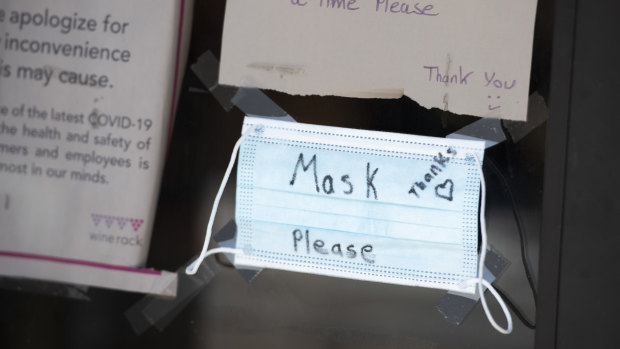 "Mask Please" is written on a protective mask hanging at a store in Ottawa, Ontario, Canada.