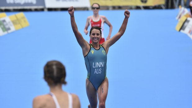 Sophie Linn of Australia raises her arms after completing the women’s individual triathlon. 