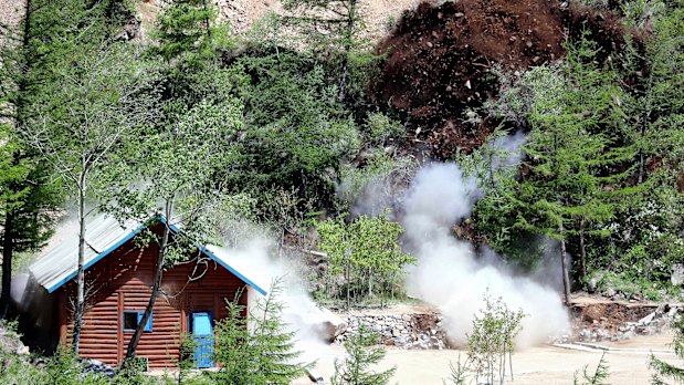 Shows smoke and debris in the air as the entrance to the tunnel at North Korea's nuclear test site is blown up.