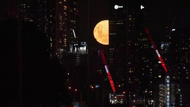 The supermoon peeks out from Melbourne buildings.