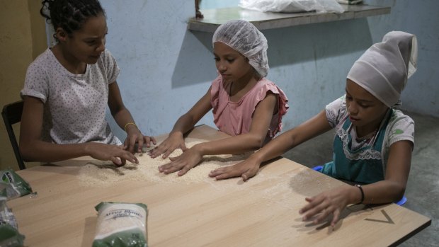 Arbeilis, 11, from left, Cardeilis Torrres, 10, and Camila Grateron, 10, clean rice infested with bugs before cooking it, at a soup kitchen in the Petare slum, in Caracas.