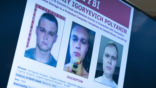 Russian Yevgeniy Polyanin, wanted by the FBI, is displayed on monitors as Attorney General Merrick Garland accompanied by Deputy Attorney General Lisa Monaco and FBI Director Christopher Wray speak in Washington. 