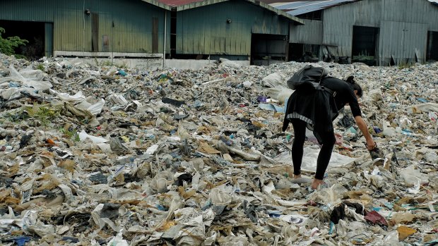 A member of the Kuala Langat environment NGO picks up  plastic waste at a shuttered illegal plastic recycling factory in Jenjarom. 