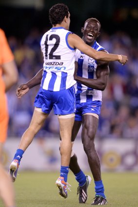 Majak Daw (right) celebrates his first AFL regular season goal with Lindsay Thomas at Etihad Stadium in 2013.