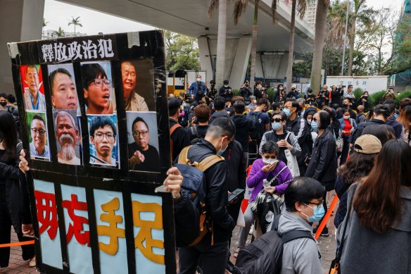 A supporter holds a sign with photos of pro-democracy activists charged under the new national security law in Hong Kong on Monday.